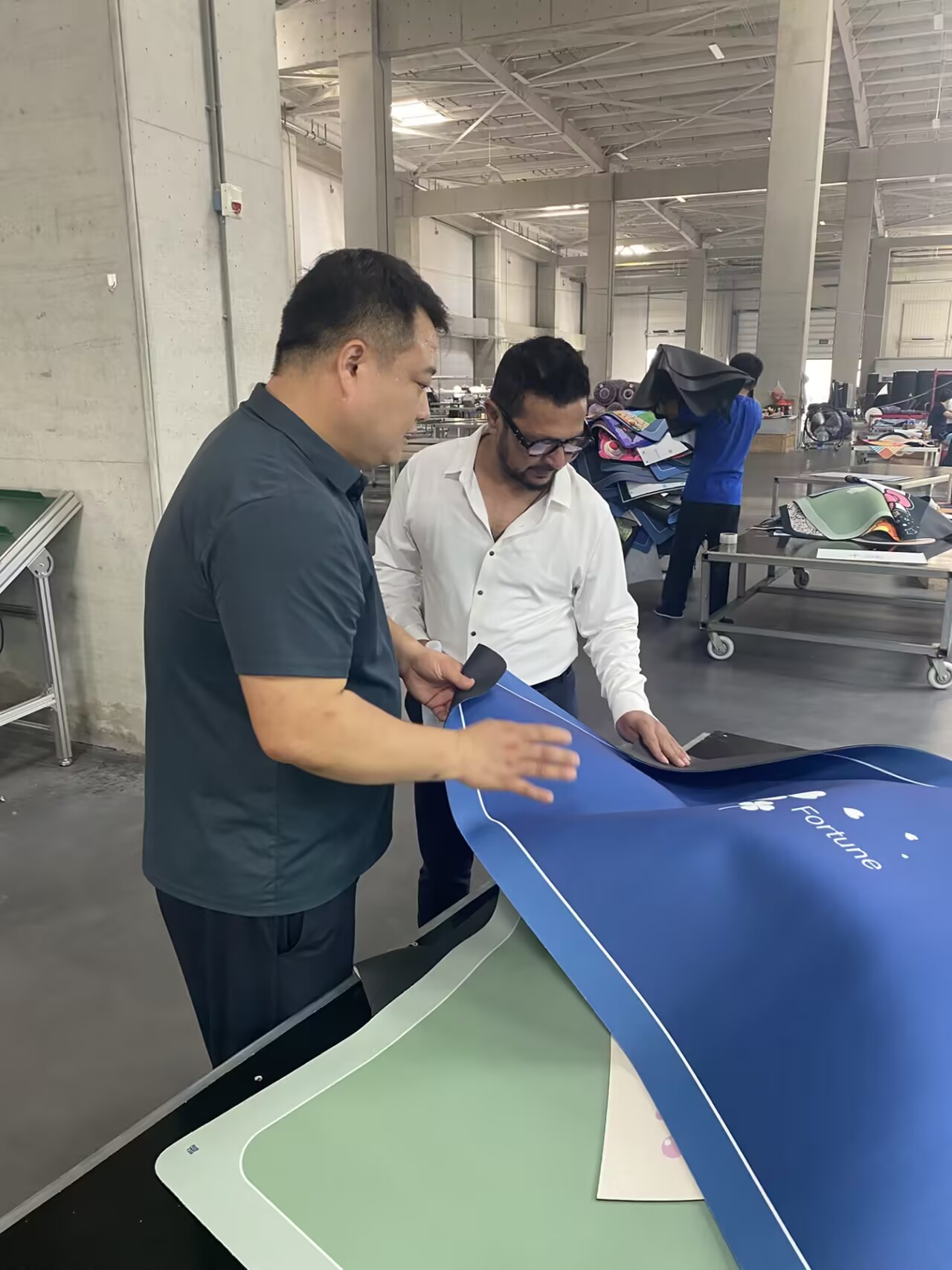Overseas buyer reviewing washable rug samples and backing in the factory