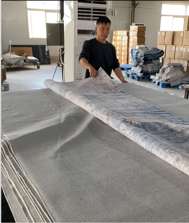 Factory worker inspecting and rolling washable rug production